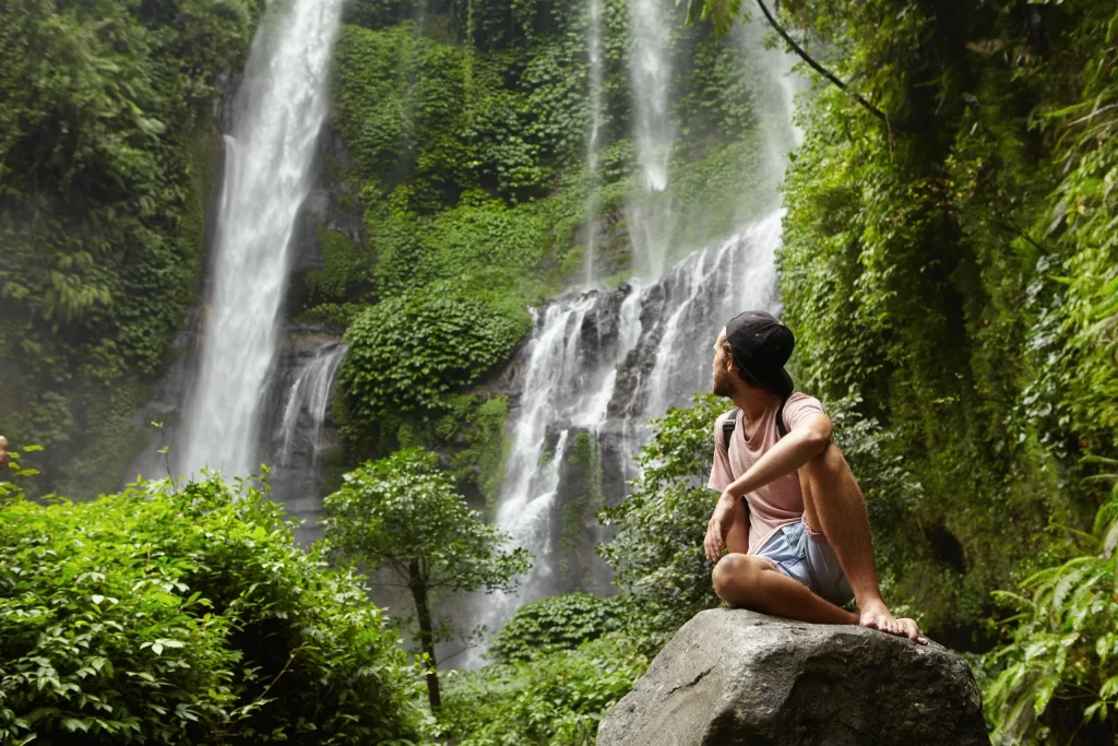 Adventurous traveler gazing at a majestic waterfall in Sri Lanka.